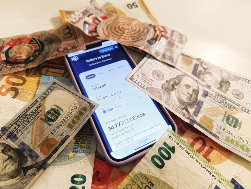 Een zakelijke professional die geld overmaakt via een laptop, met een wereldkaart op de achtergrond.